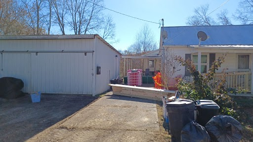 house with a open metal, flat roof carport, building materials in driveway